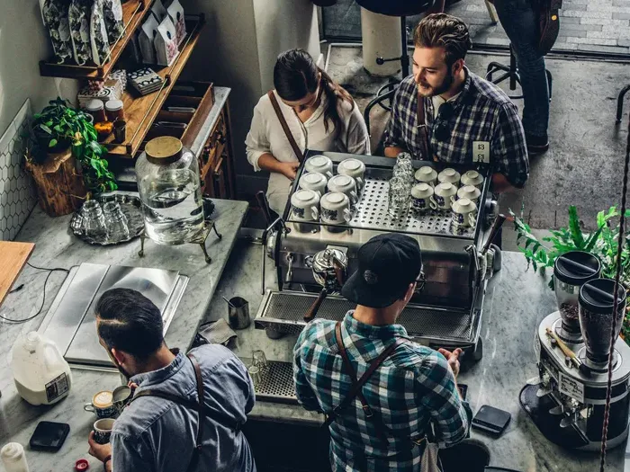 A top view of baristas and customers inside a cozy coffee shop, representing small local business community on townservicelink.net